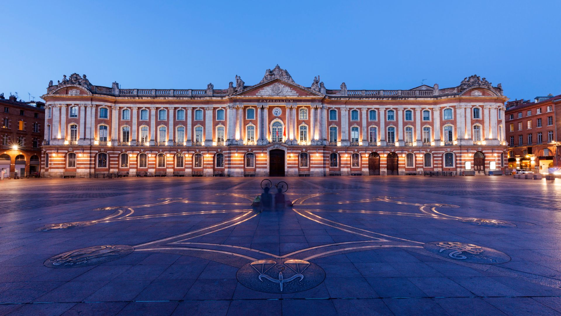 Façade du Capitole de Toulouse sous un ciel bleu, mettant en avant son architecture néoclassique avec des détails sculpturaux élégants.